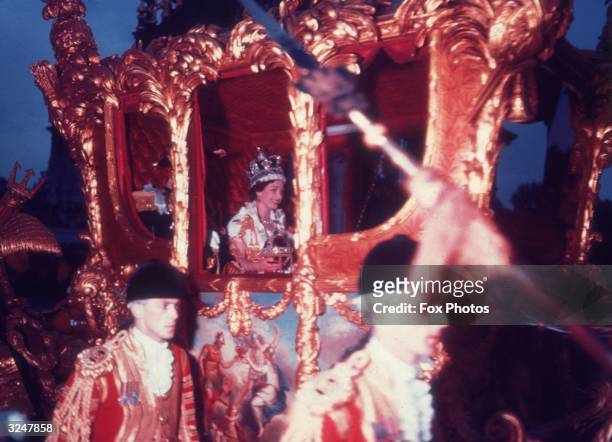 Queen Elizabeth II in the gold coronation coach after her coronation ceremony.