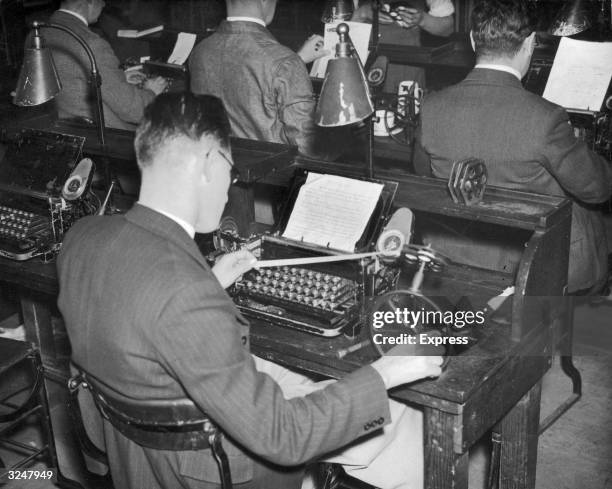 Man operating a ticker-tape machine in the wire room at the Daily Express building in Fleet Street, London.