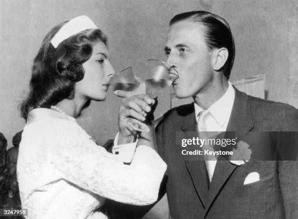 Baron Hans Heinrich von Thyssen-Bornemisza and his new bride, British fashion model Fiona Campbell-Walter, intertwine their arms for a marriage...