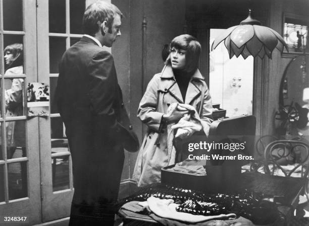 Canadian actor Donald Sutherland watches American actor Jane Fonda pack a suitcase in her apartment in a still from the film, 'Klute,' directed by...