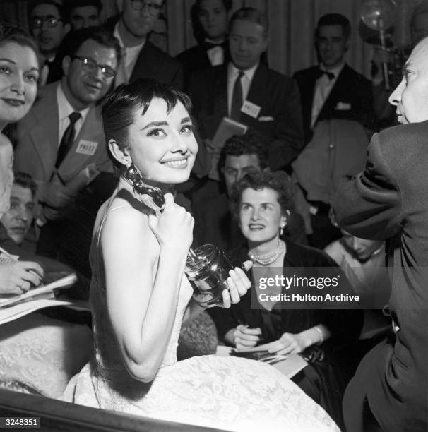Belgian-born actor Audrey Hepburn is surrounded by reporters as she holds the Best Actress Oscar she won for her role in director William Wyler's...