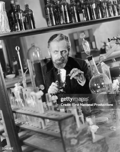 Austrian-Hungarian born American actor Paul Muni concucts an experiment in a lab in a still from the film, 'The Story of Louis Pasteur,' directed by...