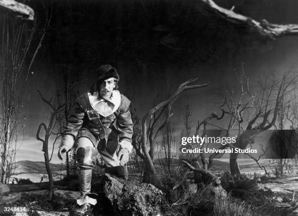 Puerto Rican-born actor Jose Ferrer crouches while walking through trees and bramble at night in a still from the film 'Cyrano de Bergera,' directed...