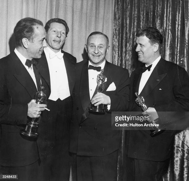 Left to right: actors Humphrey Bogart and Danny Kaye , producer Arthur Freed , and director George Stevens pose with their Oscar trophies at the...