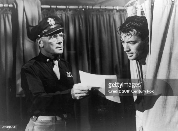 American actor Gregory Peck peers out of the shower as actor Dean Jagger holds out a telegram in a still from director Henry King's film, 'Twelve...