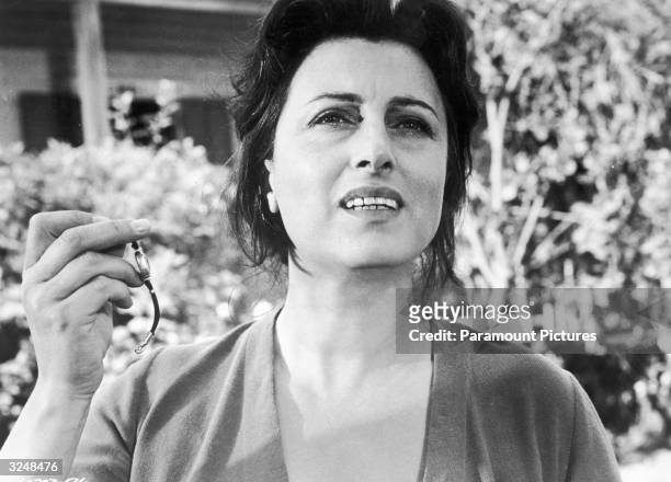 Italian actor Anna Magnani holding up a wristwatch in a still from the film, 'The Rose Tattoo,' directed by Daniel Mann.