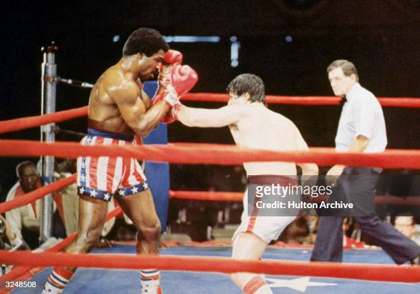 American actor Sylvester Stallone, as Rocky Balboa, punches American actor Carl Weathers, as Apollo Creed, during a boxing match in a still from the...