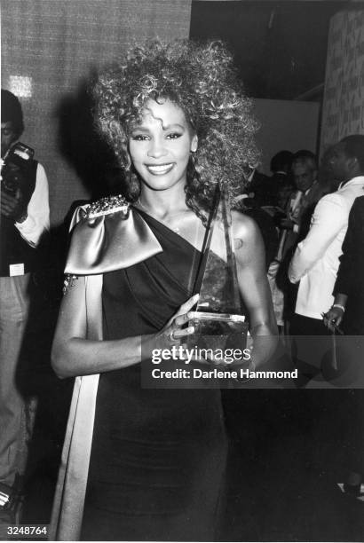 American singer Whitney Houston poses with her trophy backstage at the American Music Awards, Shrine Auditorium, Los Angeles, California.