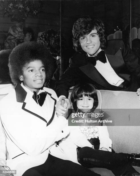 American singers Michael Jackson and Donny Osmond clasp hands while posing with child actor Ricky Segall at the American Music Awards, Beverly Hills...