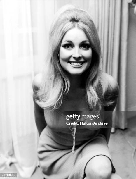 American actor Sharon Tate smiling in front of a window.