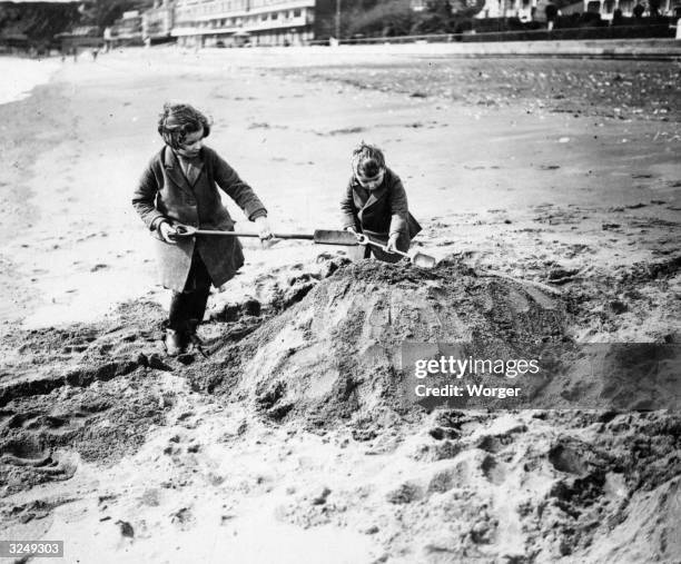 Children playing on the beach on the Isle of Wight preparing a sand castle.