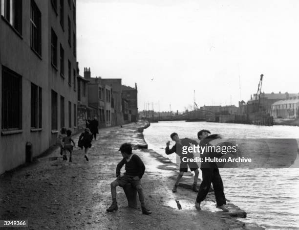 Boys throwing stones into the canal in a docklands area.