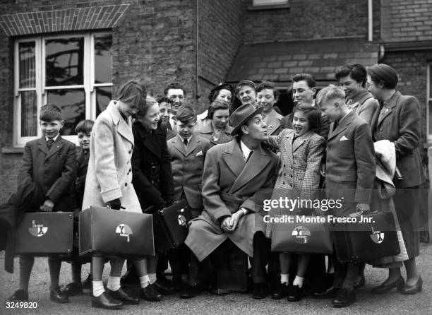 Party of 14 boys and girls who are emigrating to Australia to another Barnardos home. Tommy Trinder is there to see them off.