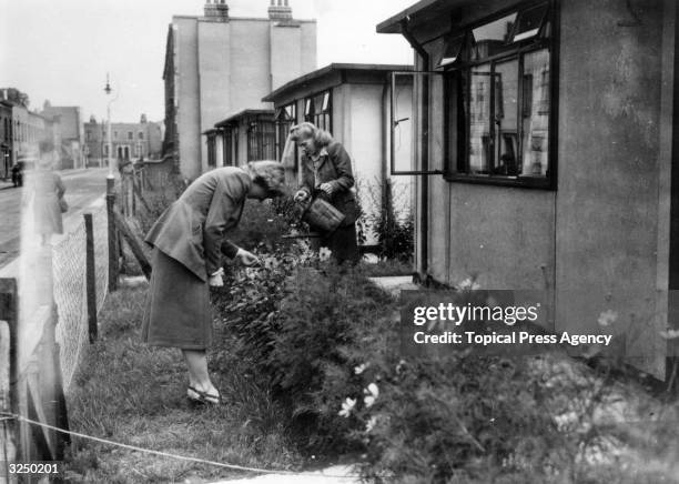 Couple of ladies tending their gardens of prefabricated houses, at Camberwell, London.