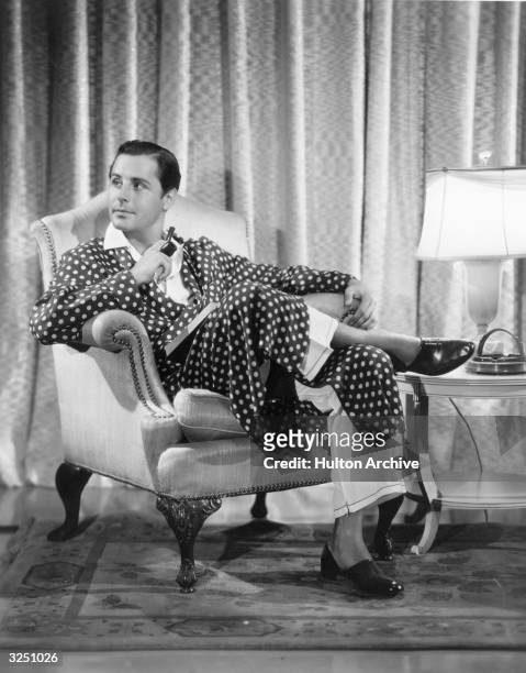 Thomas Beck, the American actor, wearing a maroon foulard robe with an off white dot pattern. The pyjamas are of natural colour chinese silk with...