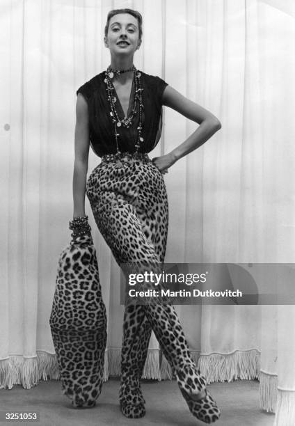 Pair of leopardskin-effect slacks which cover their matching slippers, and large cigar-shaped muff, by Parisian designer Pierre Balmain. Original...