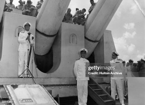 Admiral Chester William Nimitz standing beneath the 16-inch guns of HMS King George, the flagship of the British Naval forces in the Pacific fleet.