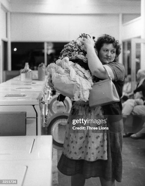 Woman with a large load of laundry in a New York laundromat.