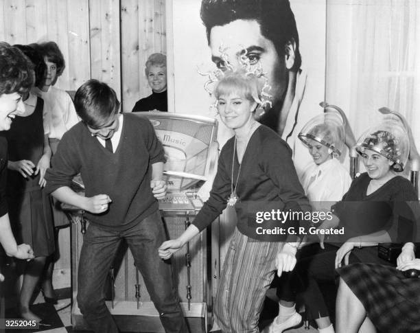 Young people dancing at a hairdressing salon opened by John French at Egham, Surrey, which caters exclusively for teenagers. It is fitted with a...