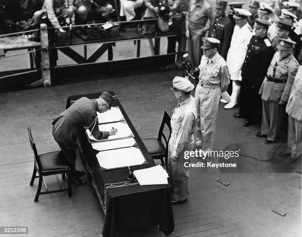 General Douglas MacArthur as Supreme Commander of the Allied Forces accepts the unconditional surrender document signed by the Japanese Yoshijiro...