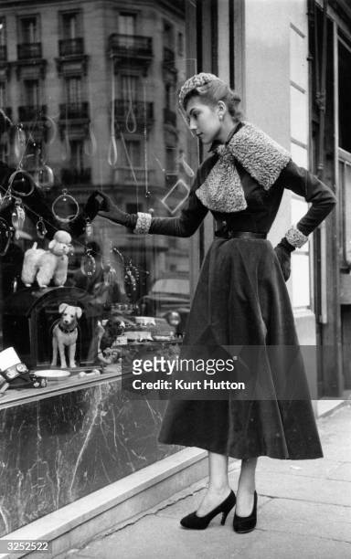 French model goes window shopping in the streets of Paris. Original Publication: Picture Post - 6685 - Paris Picks Up Her Skirts - pub. 1953