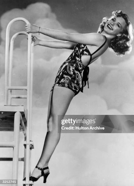 Priscilla Lane, the film actress, balancing at the top of the diving board in typical 'pin-up' pose.