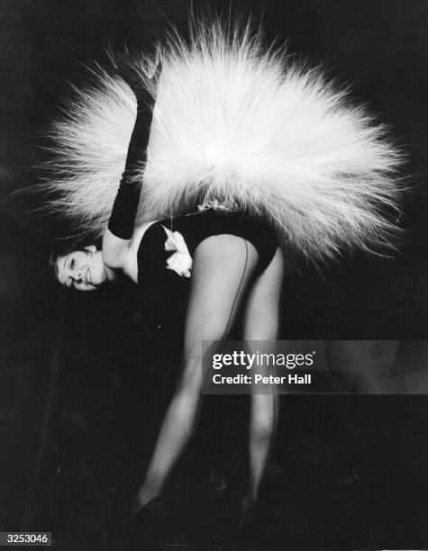French dancer Renee 'Zizi' Jeanmaire displays her £700 feather bustle made of aigrette or egret feathers, during rehearsals for the first London...