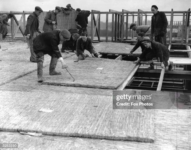Workers lay down soundproofing material on a rooftop at Pinewood Film Studios.