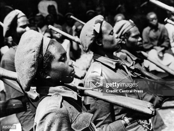 Field Marshal Mwariama's nine year old son on parade with other Mau Mau soldiers.