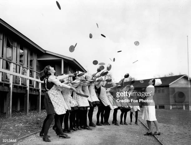 Girls evacuated from Ilford celebrate Shrove Tuesday with a traditional pancake toss.