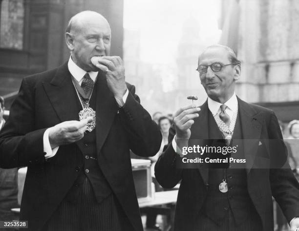 The Lord Mayor of London, Sir Harold Gillett, left, tastes a sausage at the Civil Defence Emergency Cooking Exhibition, near St Paul's. Mr Salmon,...