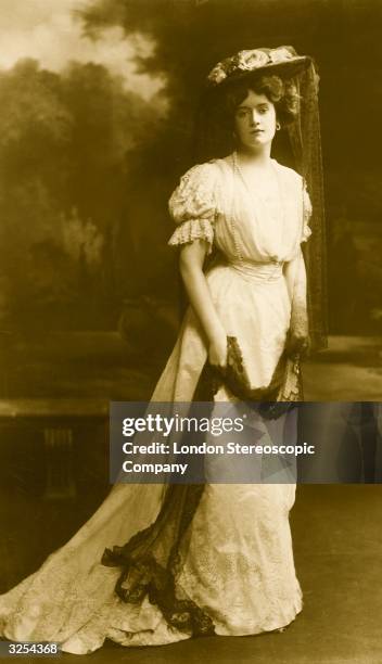 Woman wearing an Edwardian dress and hat with a lace veil.