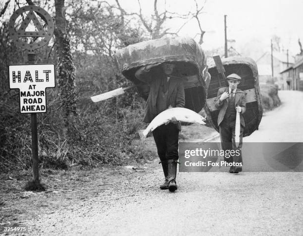 Two coracle fishermen bringing home salmon caught in the River Tivy to their village, Cenarth in Cardigan, South Wales. This method of fishing in a...