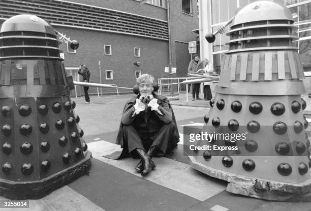 Dr Who, played by Jon Pertwee sits in the car park of the BBC guarded by two Daleks, robotic creatures from the popular tv series.