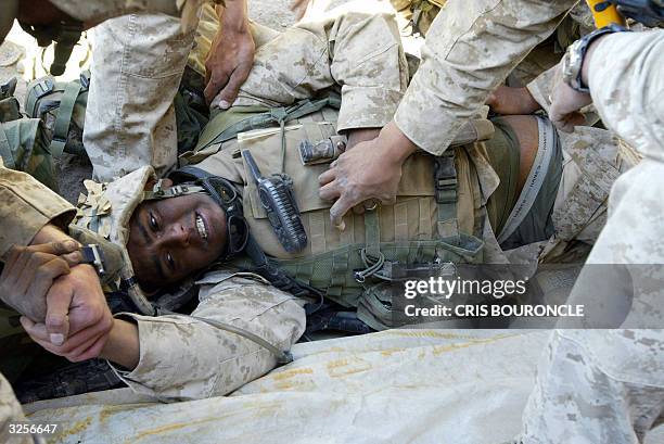 Marines give first aid to a slightly wounded comrade 08 April 2004 in the flashpoint town of Fallujah, 50 km west of Baghdad. The death toll from...