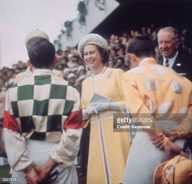 Queen Elizabeth II chats with jockeys Ron Quinton and Hilton Cope before the Queen Elizabeth Stakes at Randwick race course near Sydney, during her...