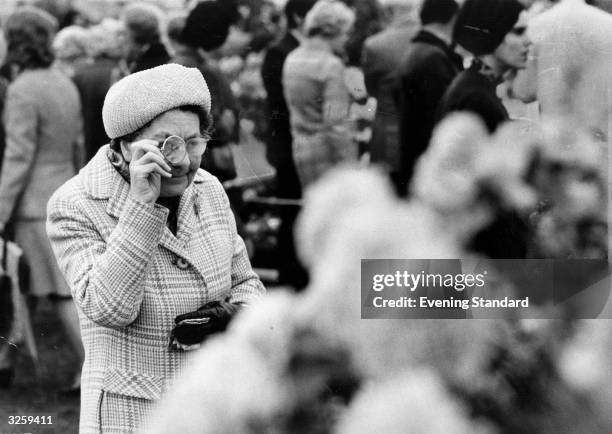 Visitor to the Chelsea Flower Show in a world of her own as she examines some blooms.