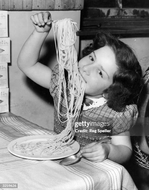 Young girl enjoying a plate of her father's spaghetti made at Messrs L Ugo Ltd, London. The factory specialises in all types of pasta and rivals the...