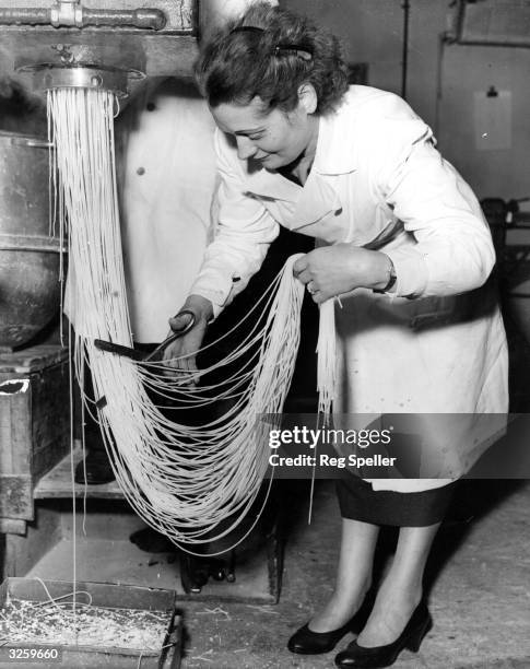 Zelda Albano cuts spaghetti into lengths as it emerges from a machine at Mess' L Ugo Ltd, a pasta making factory in Holloway, London.