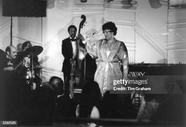 American jazz scat singer Ella Fitzgerald performing at Ronnie Scott's jazz club in London, with Joe Pass on guitar, left.