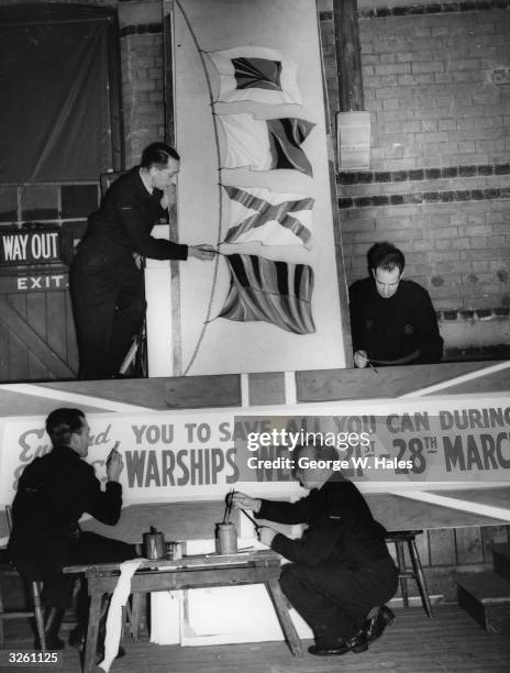 Southgate commercial display artists put the finishing touches to a banner whose flags signal 'S A V E' for Warship Week.