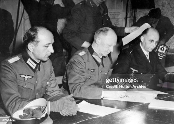German soldier and Chief of the Operations Staff Alfred Jodl flanked by his aide on the left and Grand Admiral Hans Georg von Friedeburg on the...