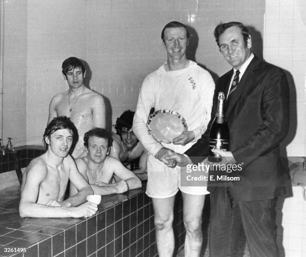 Leeds United manager Don Revie presents Jack Charlton with a bottle of champagne and the Footballer of the Month trophy in the changing room after a...