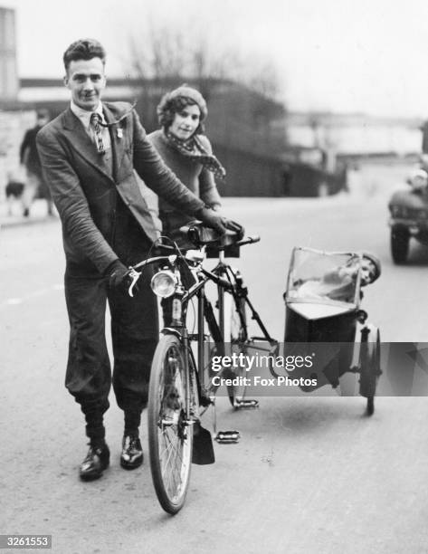 Young mother and father in South Wales take their baby for a ride in their tandem bicycle's sidecar.