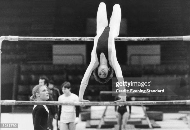 Beatrice Doucet, the 15 year old French gymnast, stretched upside down on the asymetric bars during a competition at Wembley Arena.