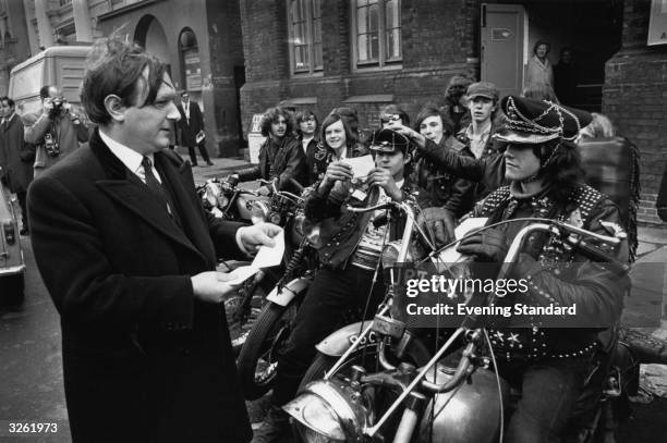 Peter Thompson of the YMCA National Council, giving letters for delivery to members of 'The Devils Henchmen', a motor cycle gang from Islington YMCA.