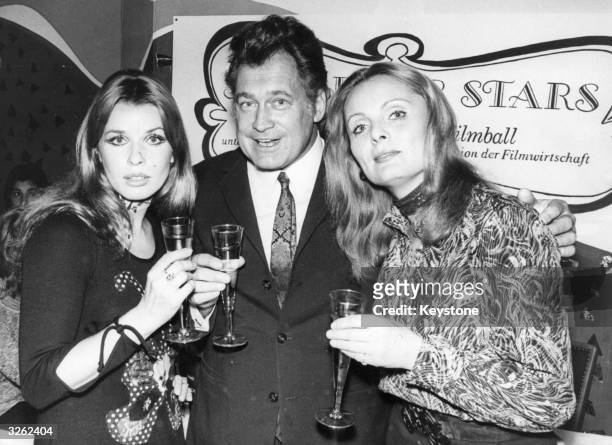 Actresses Senta Berger and Ruth-Maria Kubitschek with Carl Mohner, the art director of the Munich carnival, all drink to its new event, a charity...