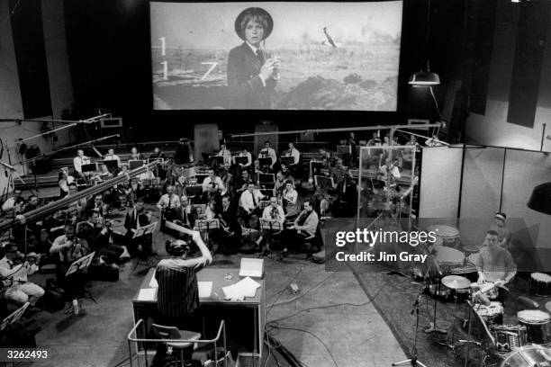 Malcolm Arnold conducts a 70-piece orchestra as they record music onto the film track for 'The Battle of Britain'. The score, by Sir William Walton,...