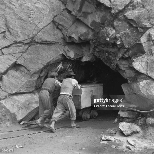 Miners pushing an ore car into the Grace tin and tungsten mine in Bolivia.