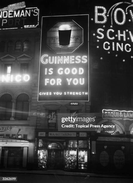 An electric light sign advertising Guinness at Piccadilly Circus, London.